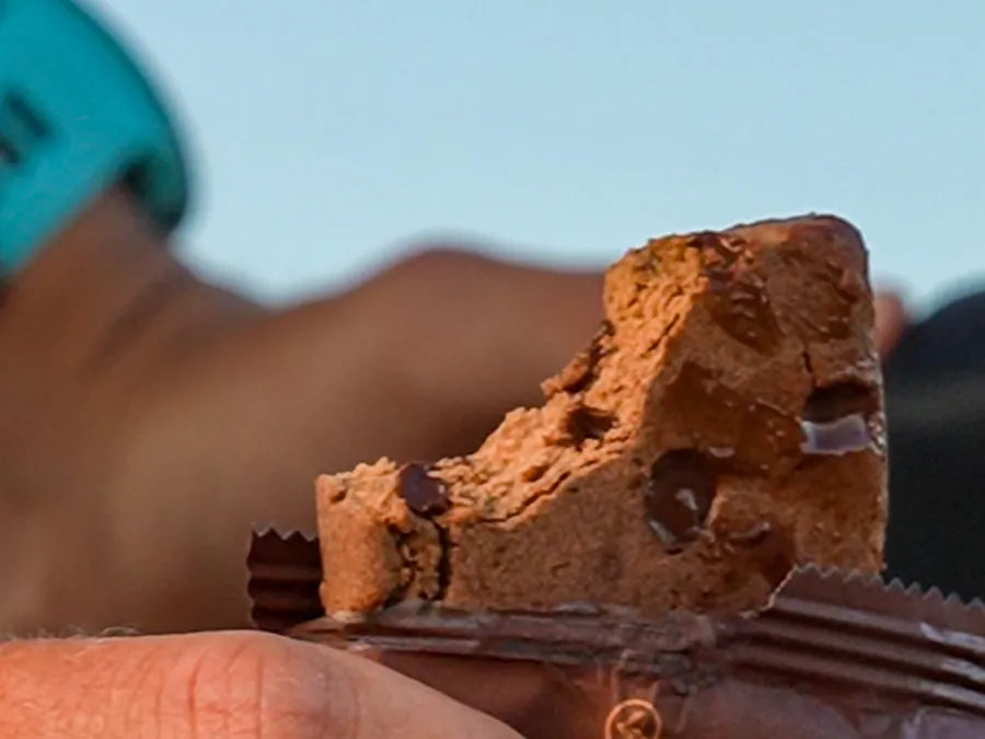 ADDRA bar broken open in an athlete's hand, showing the soft chewy interior and chocolate pieces